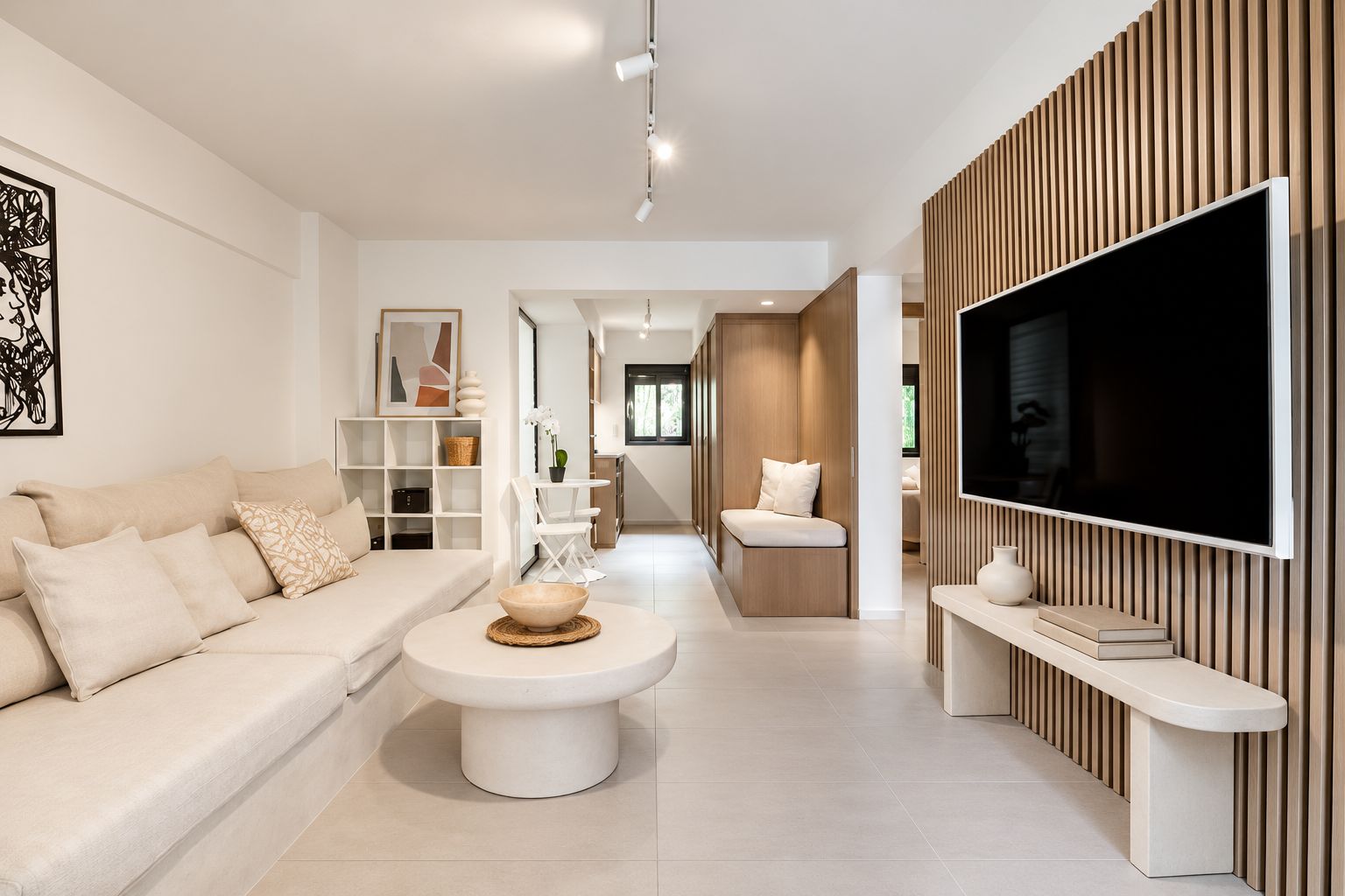 A modern living room with a sofa, a coffee table, and a TV mounted on a wooden wall.