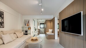 A modern living room with a sofa, coffee table, TV, and a wooden panel wall. - Directly before the sea.Direkt vor dem Meer (Vouliagmeni)