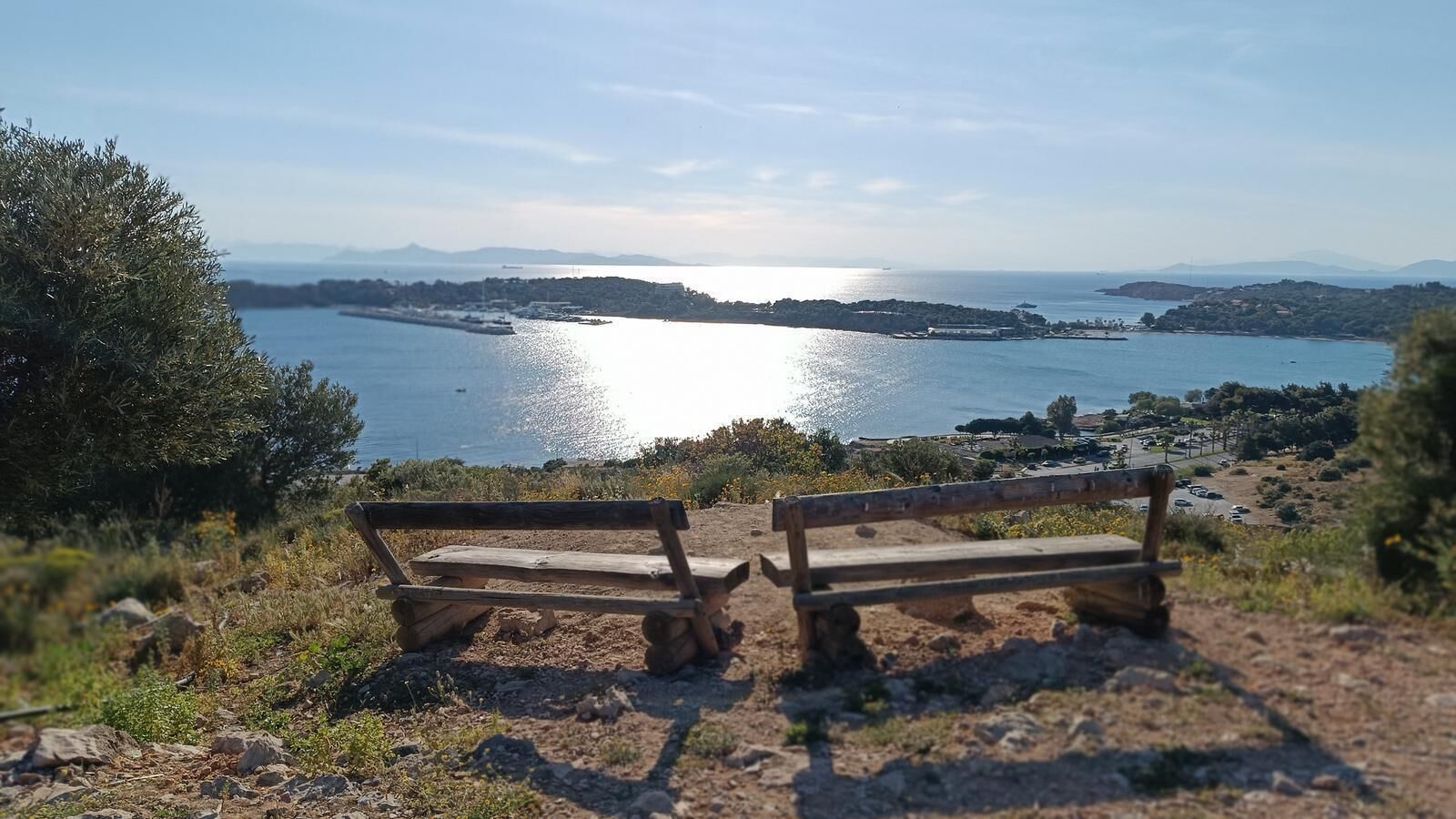 Eine Bank mit Blick auf eine Küstenlandschaft und die See sowie entferntes Land.