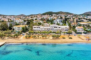 A coastal town with a beachfront hotel featuring multiple floors, a sandy beach, and clear blue waters. - Directly before the sea.Direkt vor dem Meer (Vouliagmeni)