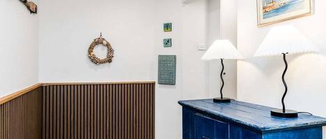 A hallway with a wooden panel wall, a blue cabinet, and wall-mounted lamps.