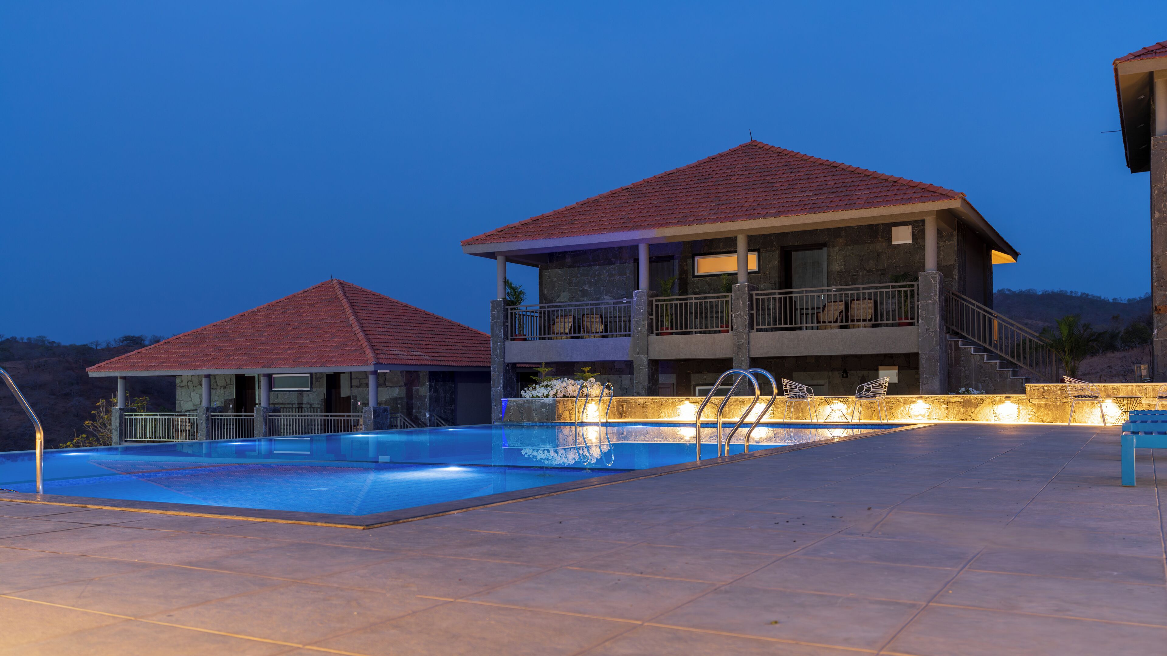 Una piscina con un edificio de dos pisos al fondo.