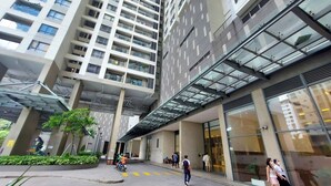 A modern high-rise building with a glass facade and a covered entrance area. - Gold View Quan 4 Aparment (Ho Chi Minh City)