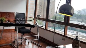 A room with large windows, a desk, a chair, and a lamp. - Aparts4Days 2 Bedroom Apart San Isidro (Lima)