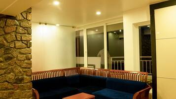 Una sala moderna con un sofá modular, una mesa de centro de madera y una pared de acento de piedra.
