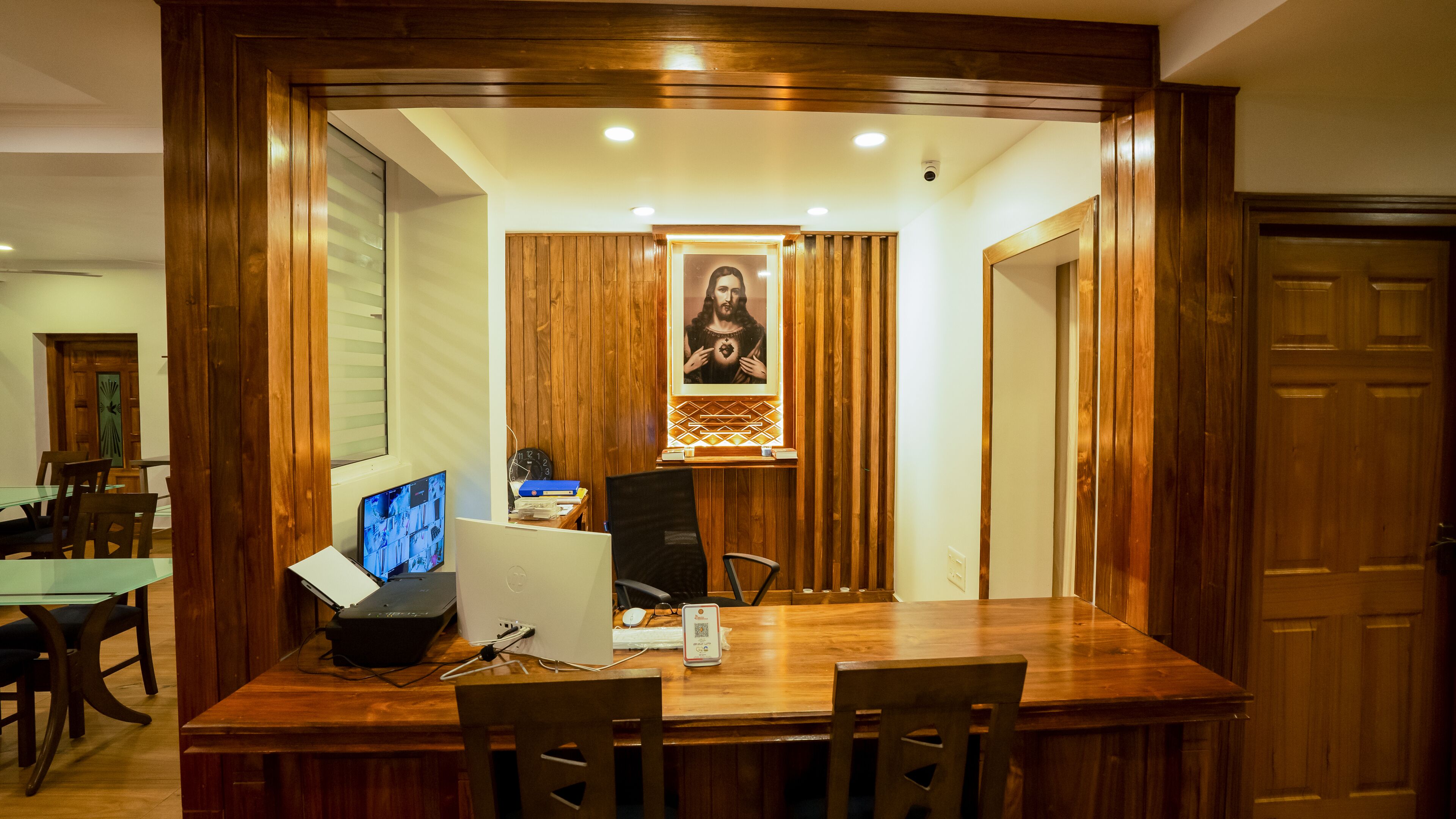 A conference room with a wooden table, chairs, a computer, and a framed picture on the wall.