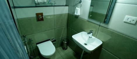 A compact bathroom with a toilet, sink, and glass shower enclosure.
