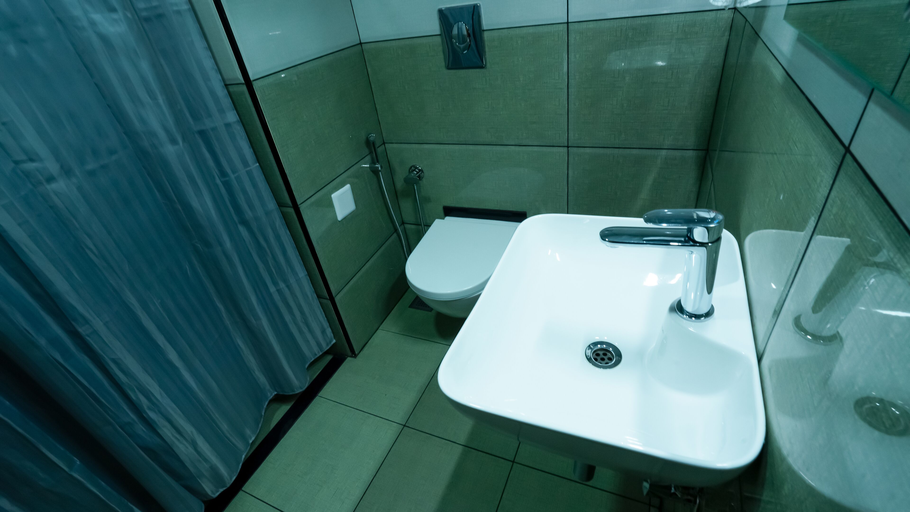 Ein kleines Badezimmer mit einem weißen Waschbecken, einer Toilette und einer Duschkabine.