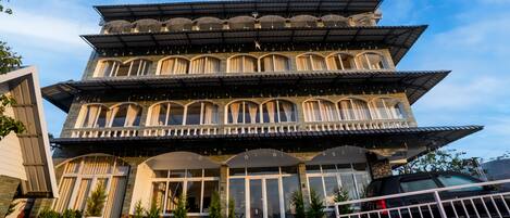 A multi-story hotel with a traditional architectural style, featuring balconies with curtains and star decorations.