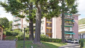 A residential building with balconies, a paved pathway, and surrounding greenery. - Blu View Apartment in Salo (Salò)