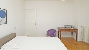A bedroom with a bed, a chair, a table, and a door. - Blu View Apartment in Salo (Salò)