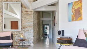 A modern living room with a stone wall, a glass coffee table, and a colorful geometric rug. - La Demeure de Saint Fiacre (Saint-Fiacre-sur-Maine)