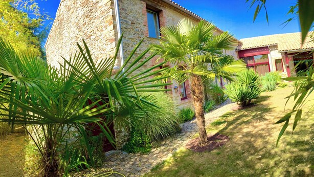 A stone building with a red door, surrounded by lush greenery and a cobblestone path. - La Demeure de Saint Fiacre (Saint-Fiacre-sur-Maine)