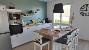 Una cocina moderna con armarios blancos, horno empotrado y un ventanal grande.