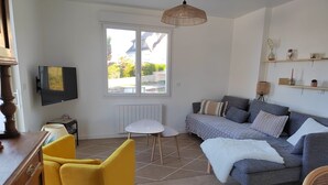 Una sala de estar moderna con un sofá, sillones amarillos, un televisor y un ventanal grande.