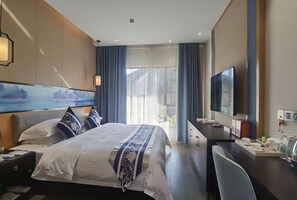 A hotel room with a large bed, a desk with a TV, and a window with curtains. - Guizhou Fenglin Yueshan Hotel (Qianxinan Buyei and Miao)
