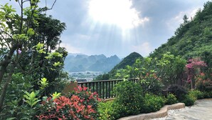 A garden with a wooden fence, various plants, and a view of distant mountains. - Guizhou Fenglin Yueshan Hotel (Qianxinan Buyei and Miao)