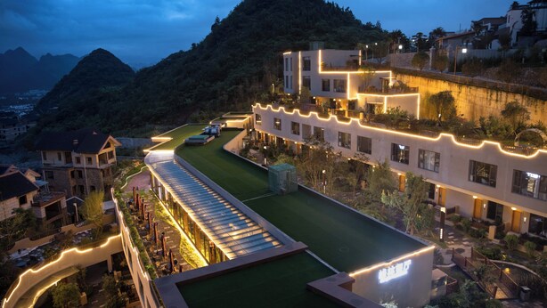 A modern hotel with a rooftop garden, a pool, and a view of surrounding hills. - Guizhou Fenglin Yueshan Hotel (Qianxinan Buyei and Miao)