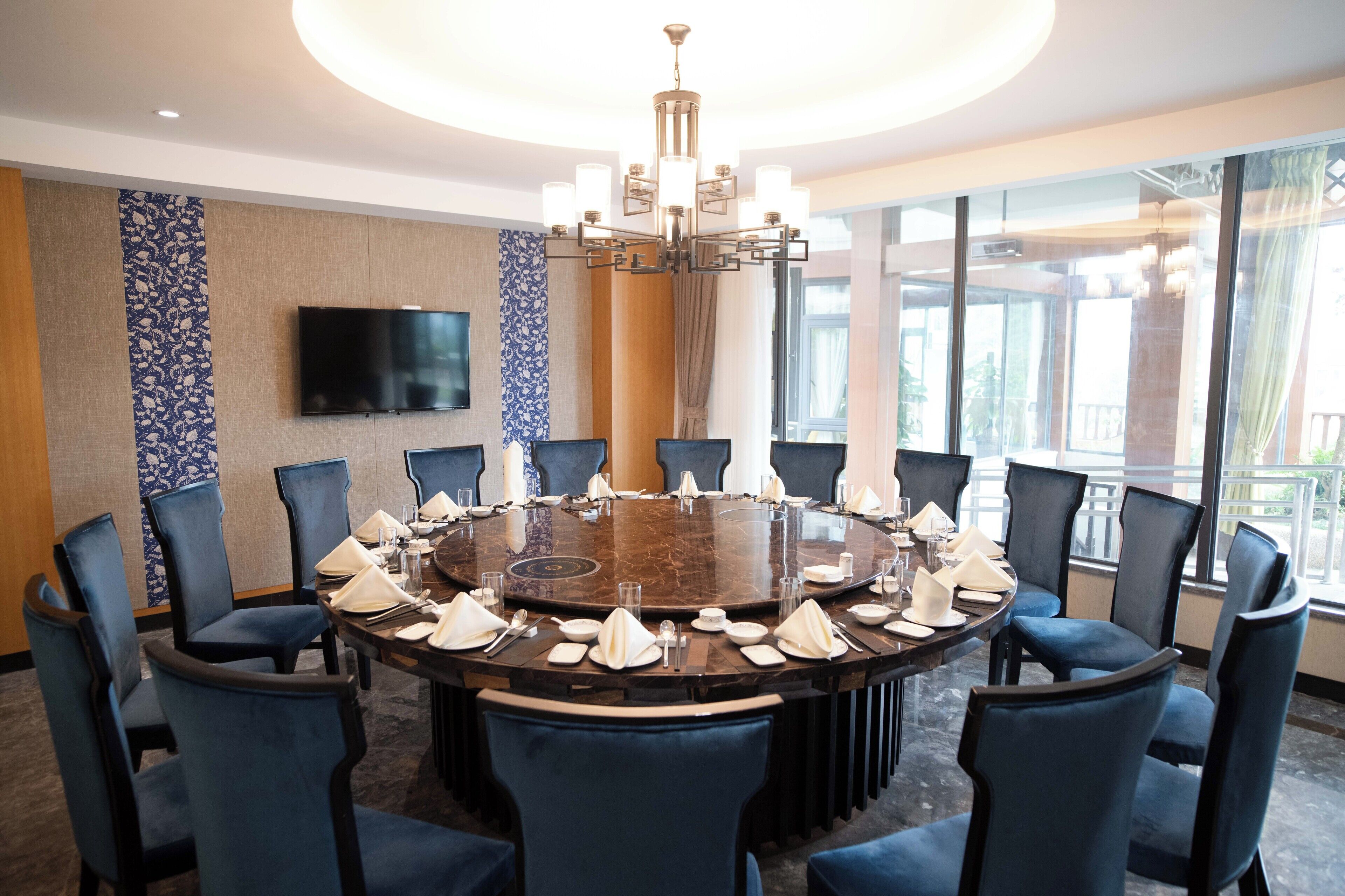 A conference room with a round table, blue chairs, and a chandelier.