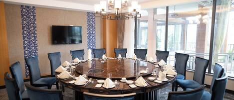 A conference room with a round table, blue chairs, and a chandelier.