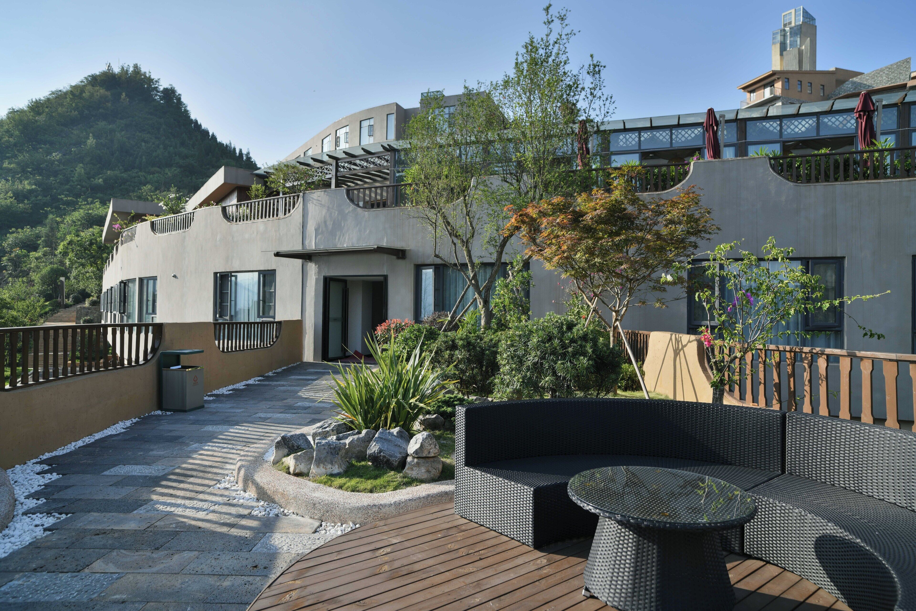 Un edificio moderno con balcón, zona de estar exterior y vistas a una colina.