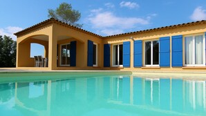 Blick auf einen Pool vor einem Gebäude, mit einer überdachten Terrasse und blauem Himmel.