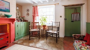 Une pièce chaleureuse avec une porte verte, une cheminée rouge et un tapis à motifs.