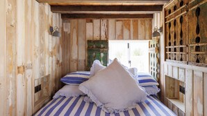Une pièce rustique en bois, avec un lit agrémenté de draps à rayures et de coussins décoratifs.