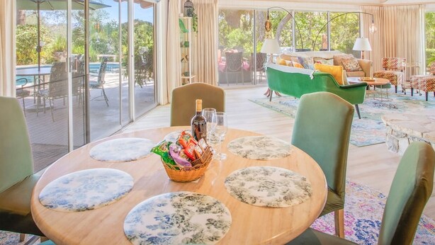 Une salle à manger spacieuse avec un plafond en bois, de grandes fenêtres et une vue sur l’extérieur.