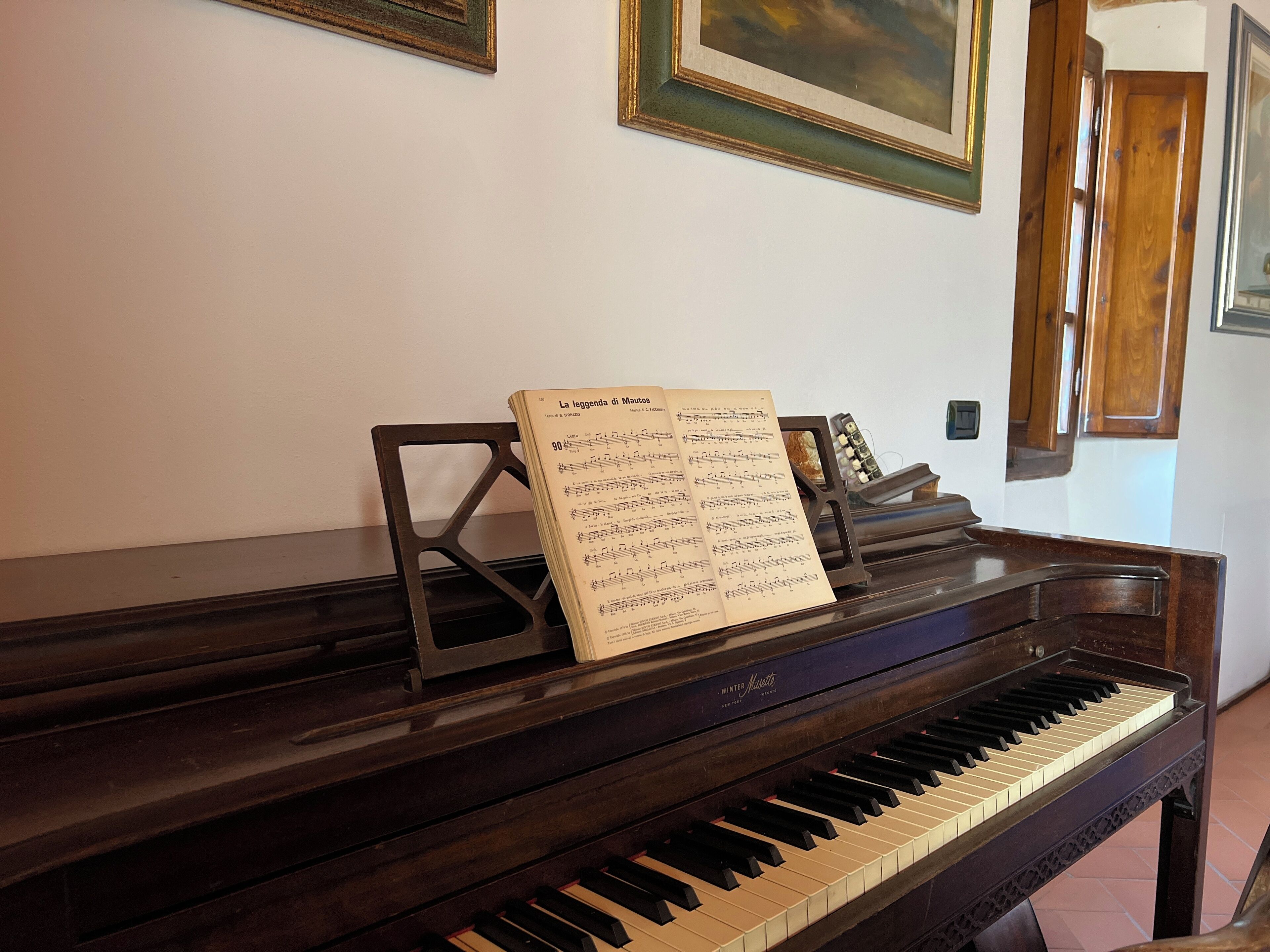 A piano with sheet music on it, placed in a room with wooden walls and framed pictures.