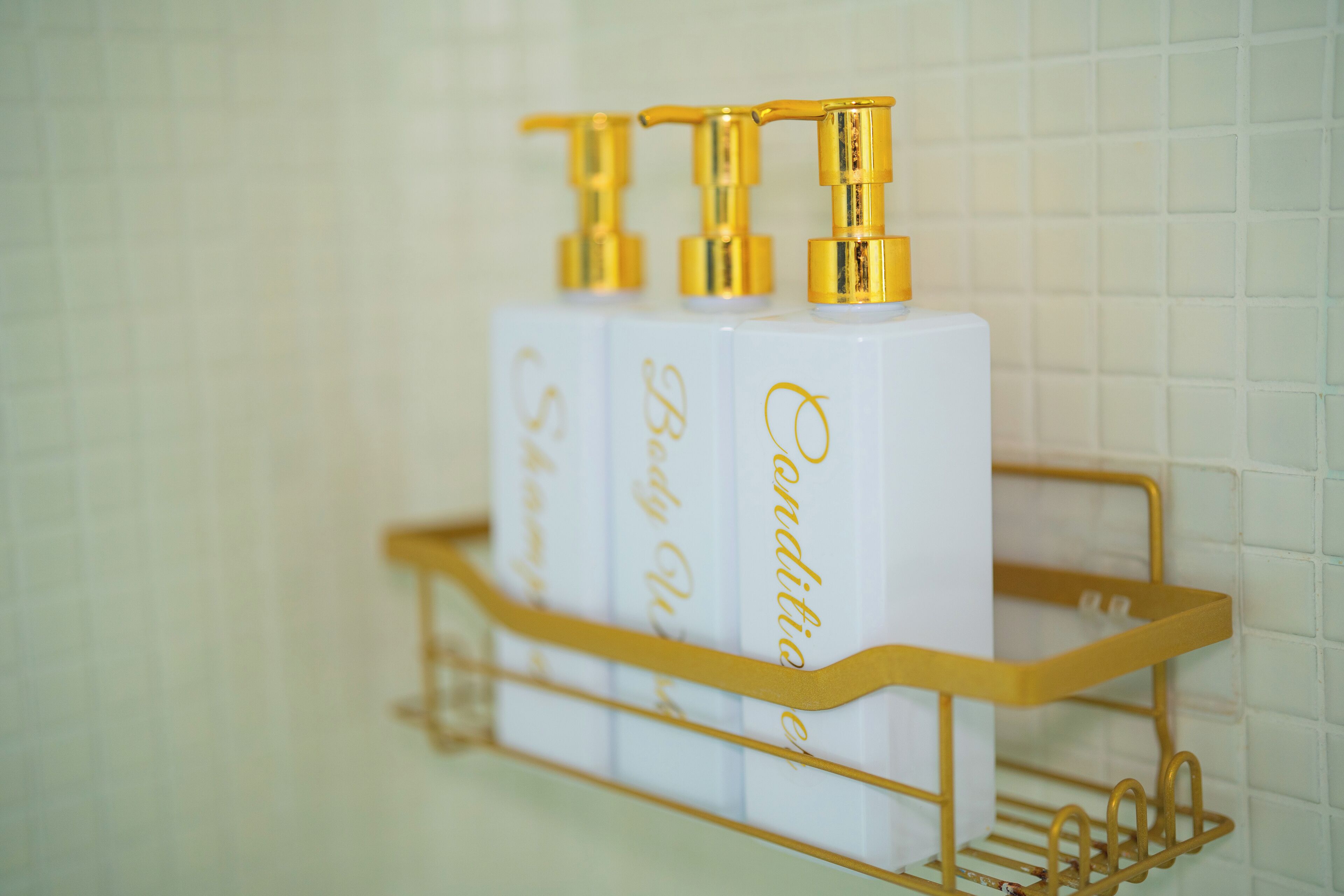 A bathroom shelf with three bottles of body lotion.