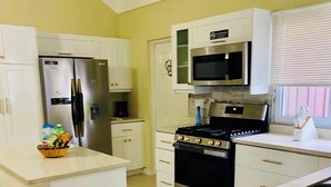 A kitchen with white cabinets, a stainless steel refrigerator, a microwave, and an oven.
