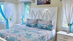 A bedroom with a bed, nightstands, a dresser, a painting, and a ceiling fan.