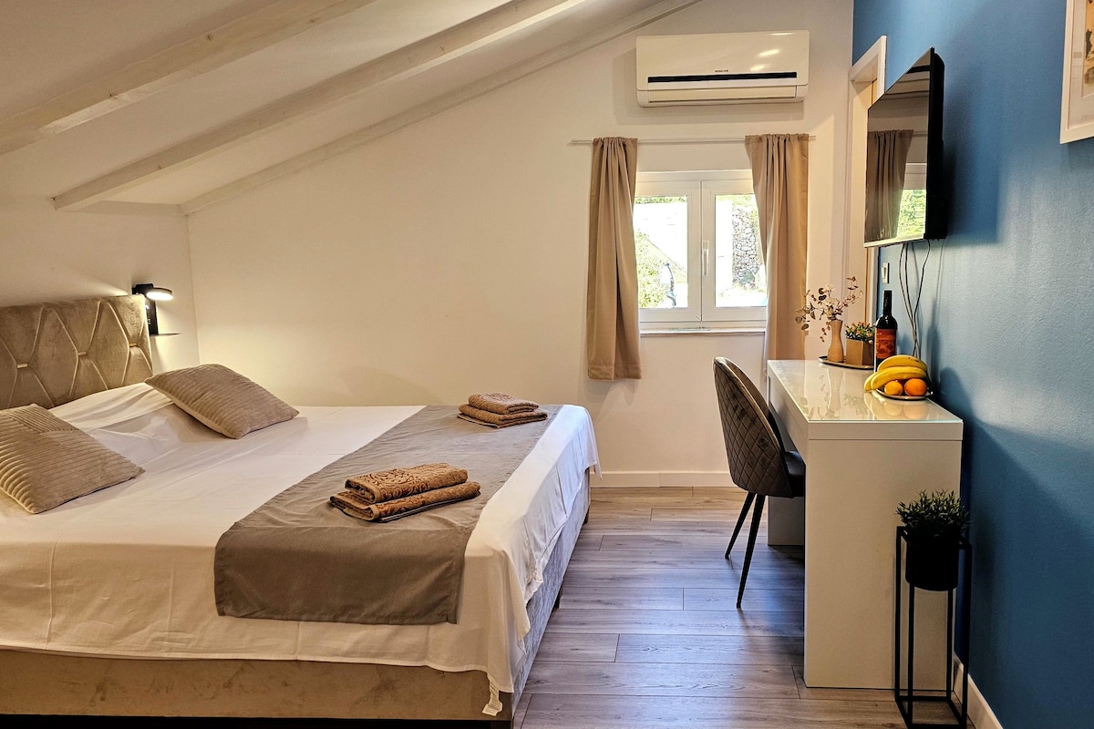 Un dormitorio con cama, mesita de noche, escritorio, silla y aire acondicionado.