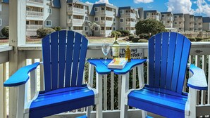 Deux chaises Adirondack bleues, une petite table placée entre elles, une bouteille de vin et un livre intitulé « Pong Off Dock ».