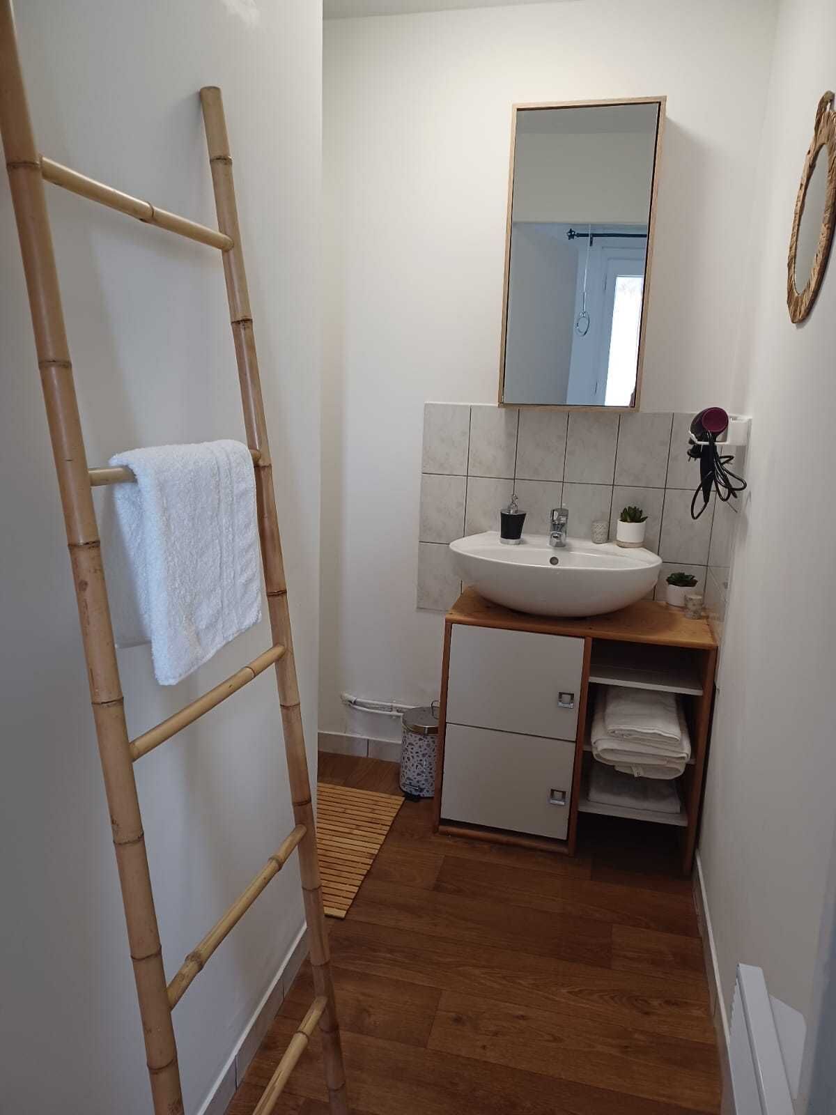 A bathroom with a wooden ladder, a white sink, a mirror, and a tiled wall.