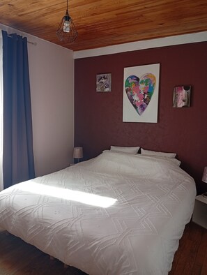 A bedroom with a large bed, wooden ceiling, and a wall with two artworks. - Logis des Pivoines Maison Proche Le PAL (Trézelles)