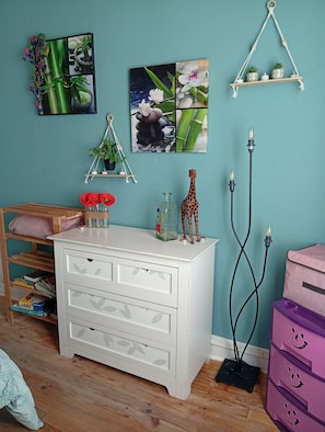 A room with a white dresser, a shelf with plants, a giraffe figurine, and a wall-mounted picture. - Logis des Pivoines Maison Proche Le PAL (Trézelles)