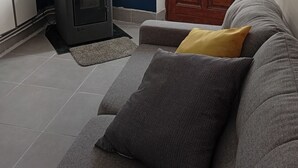 Ein Wohnzimmer mit einer Couch, einem schwarzen Kaminofen, einer blauen Wand und einer Holztür.