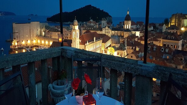 Mesa para dos, con una vela, con vistas a un pueblo costero al anochecer.