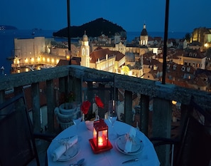 A table set for two with a candle, overlooking a coastal town at dusk. - Apartment Little Star (Dubrovnik)