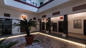 A spacious indoor courtyard with a tiled floor, potted plants, and a modern design. - Heart Of The City By Rashmi (Jaipur)