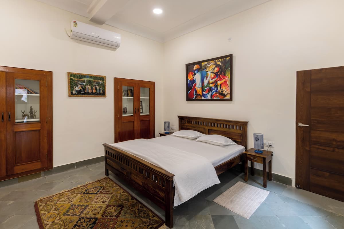 Un dormitorio con una cama de madera, una mesita de noche, un aire acondicionado de pared y dos puertas.