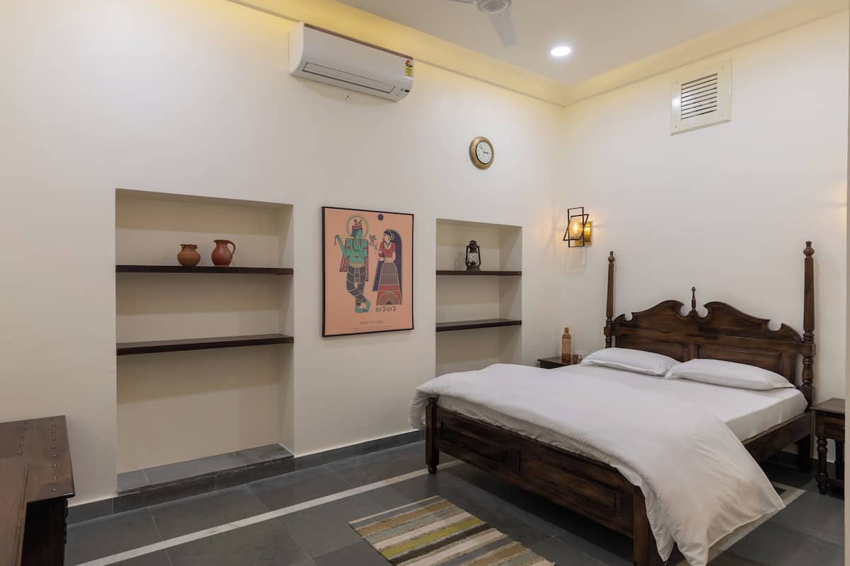 Un dormitorio con cama de madera, un reloj, estantes con objetos decorativos y un aire acondicionado de pared.