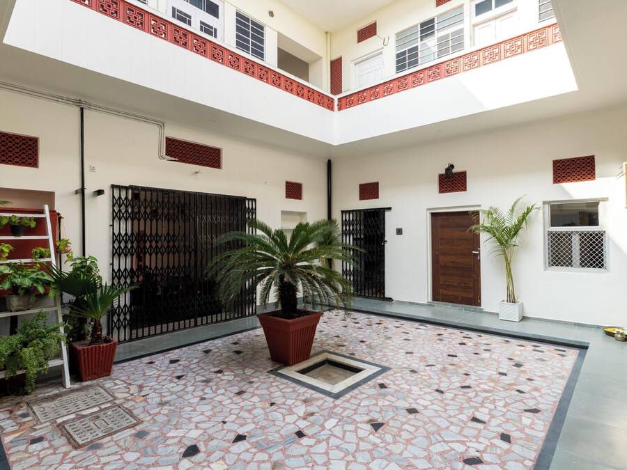 Un patio con suelo de baldosas, plantas en macetas y una reja de metal.