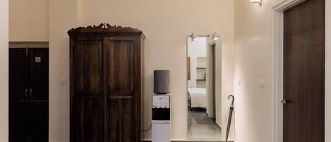A hallway with a wooden wardrobe, a water dispenser, and a door leading to a room.