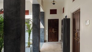 A hallway with dark pillars, a tiled floor, and a ceiling light fixture. - Heart Of The City By Rashmi (Jaipur)