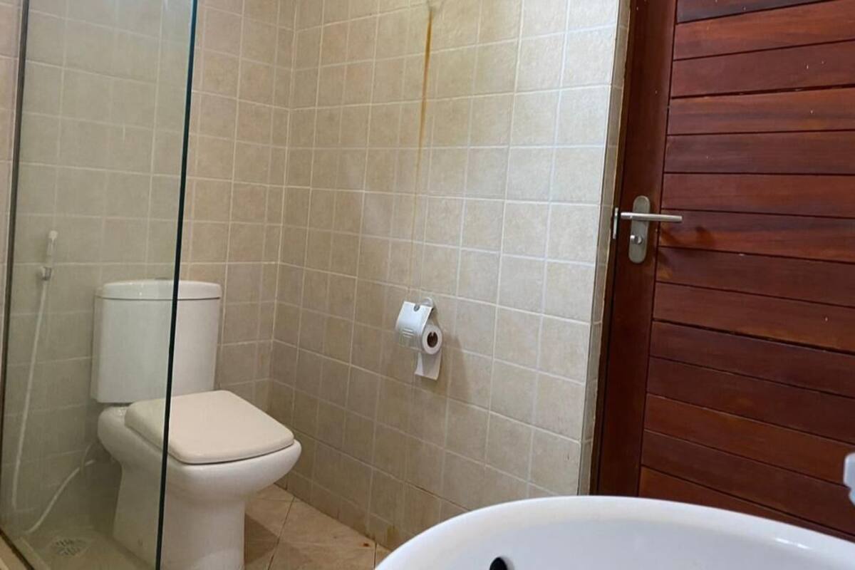 A bathroom with a toilet, a glass shower enclosure, and a wooden door.