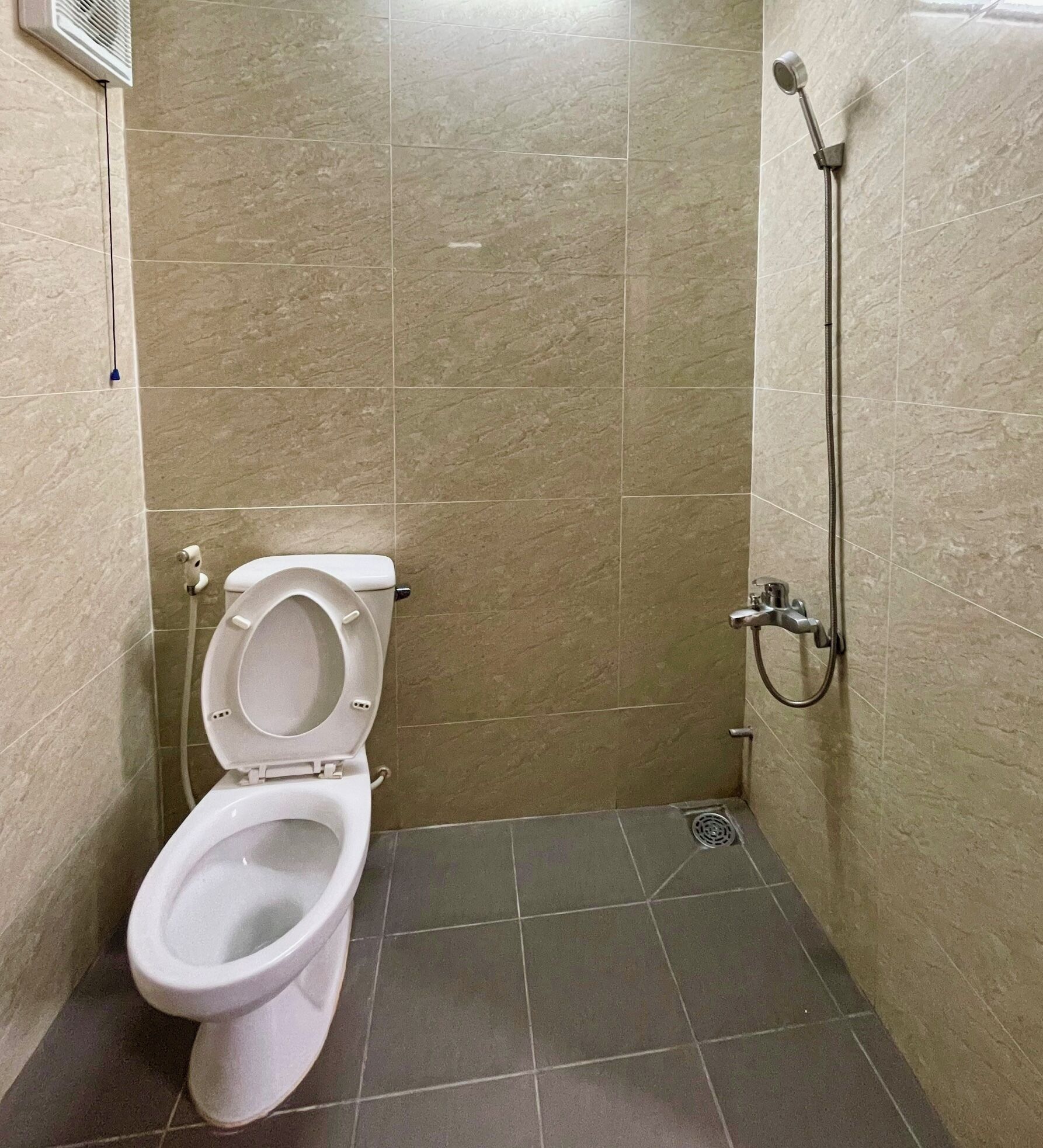 A small bathroom with a toilet, a shower, and tiled walls.