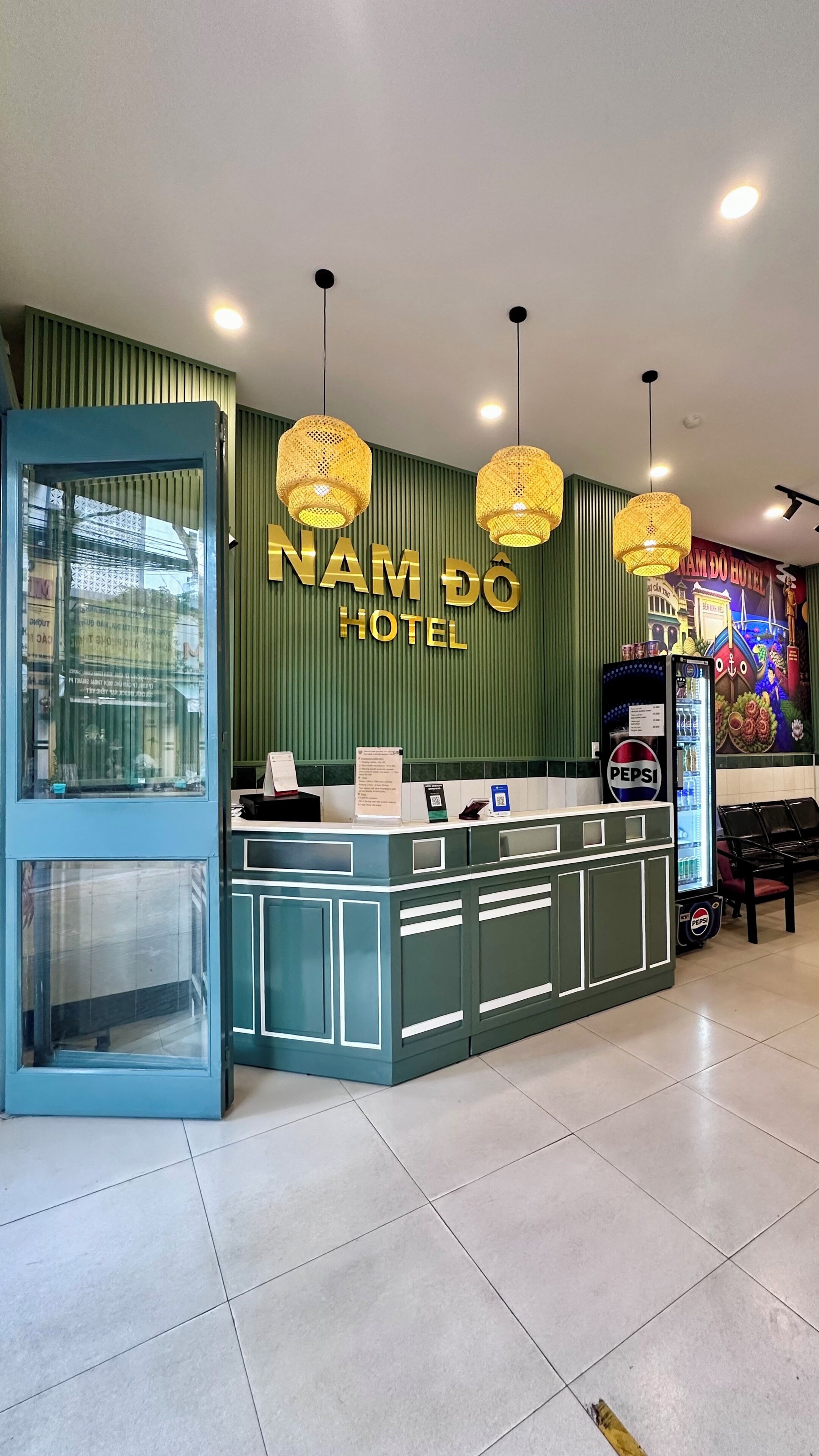 Een receptiebalie met een groene muur en een bordje met de tekst 'NAM DO HOTEL'.